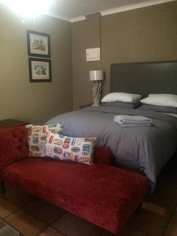 a bedroom with a bed and a red couch at Anna Katarina in Sabie