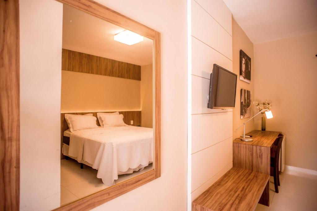 a bedroom with a bed and a mirror at Hotel Parque do Sol in Parnamirim