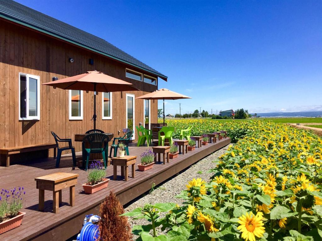einen Garten mit Tischen, Stühlen und Sonnenblumen in der Unterkunft Country Cottage Wakiaiai in Nakafurano