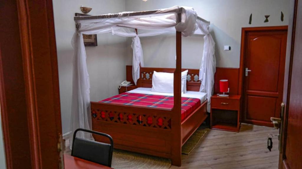 a bedroom with a wooden bed with a canopy at Parachichi House BNB in Arusha