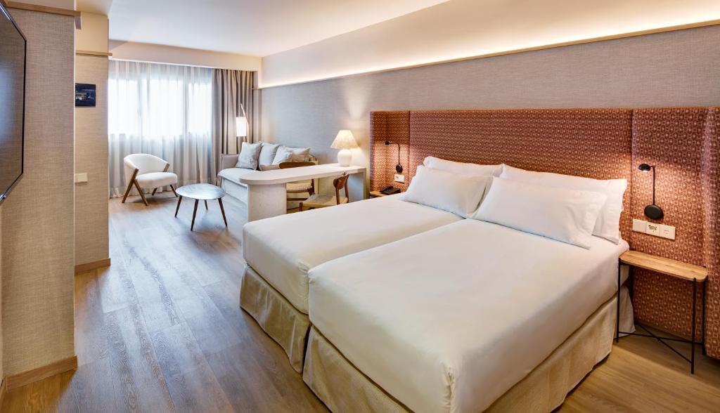 a hotel room with a large bed and a desk at Sercotel Pozuelo in Pozuelo de Alarcón