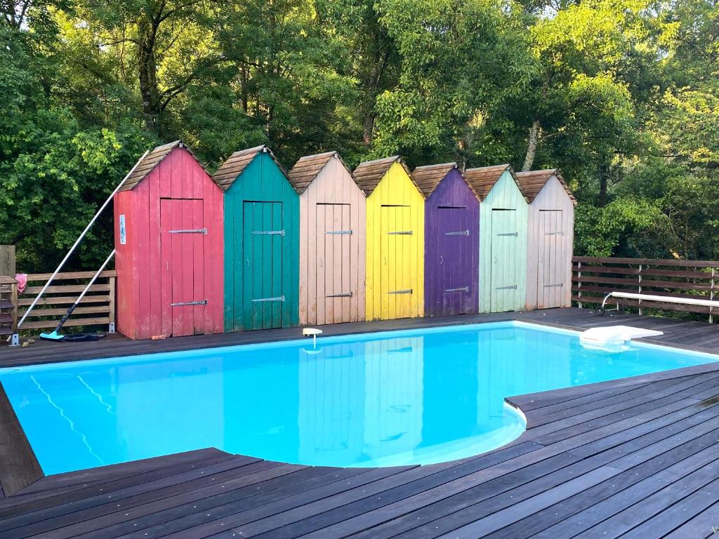 uma fila de coloridas cabanas de praia ao lado de uma piscina em Les Cabanons em Dardilly