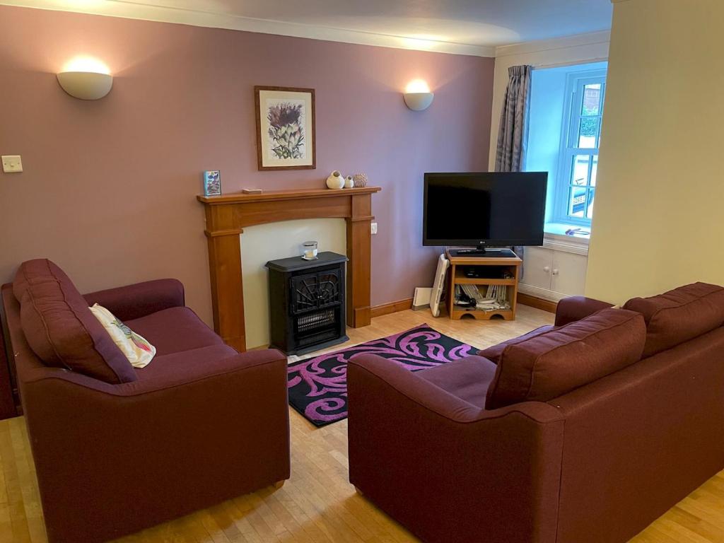 Sala de estar con 2 sofás y TV en Pass the Keys Charming 3br Listed Cottage in Historic Wigtown en Newton Stewart