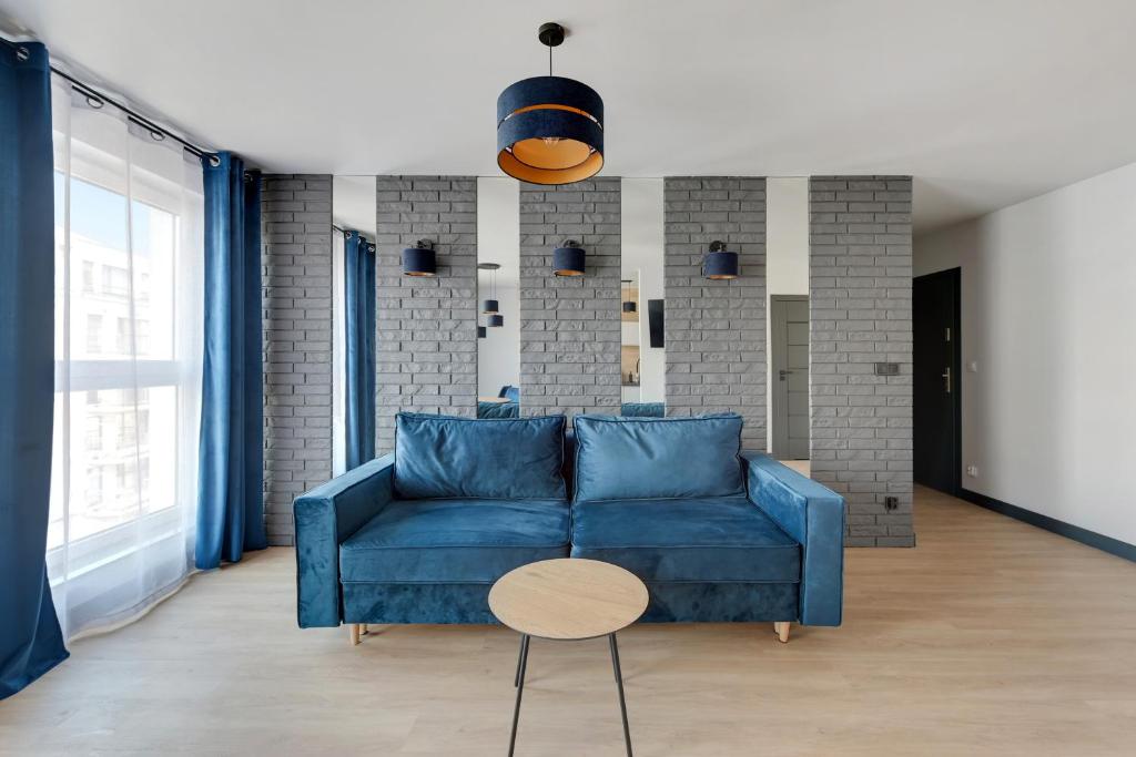 a living room with a blue couch and a table at Angielska Grobla 5 Apartinfo Apartments in Gdańsk