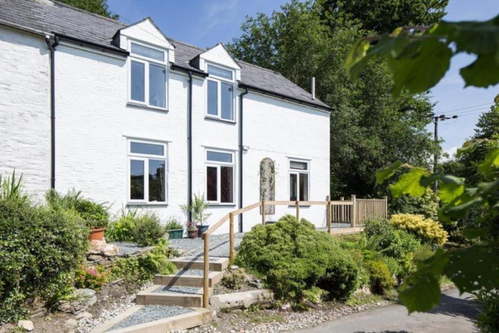 a white house with a wooden staircase in front of it at Drovers Cottage in Tavistock