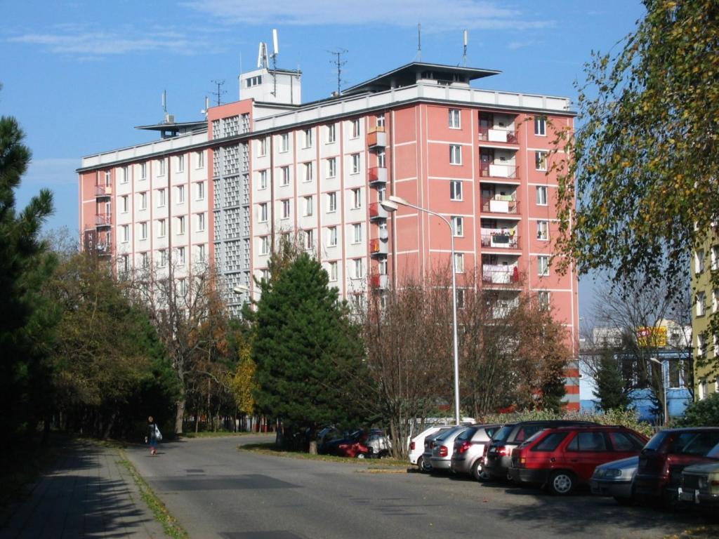 een groot roze gebouw met auto's geparkeerd op een parkeerplaats bij Hotelový Dům in Olomouc