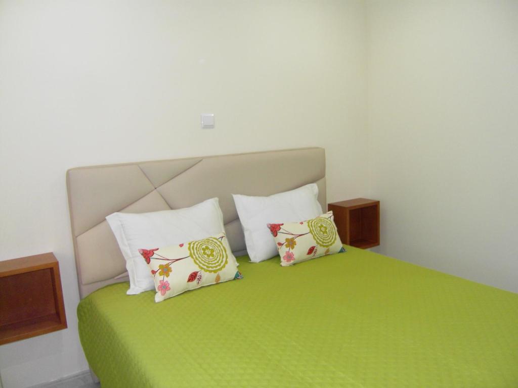 ein Schlafzimmer mit einem grünen Bett mit vier Kissen in der Unterkunft Muralha House in Lagos