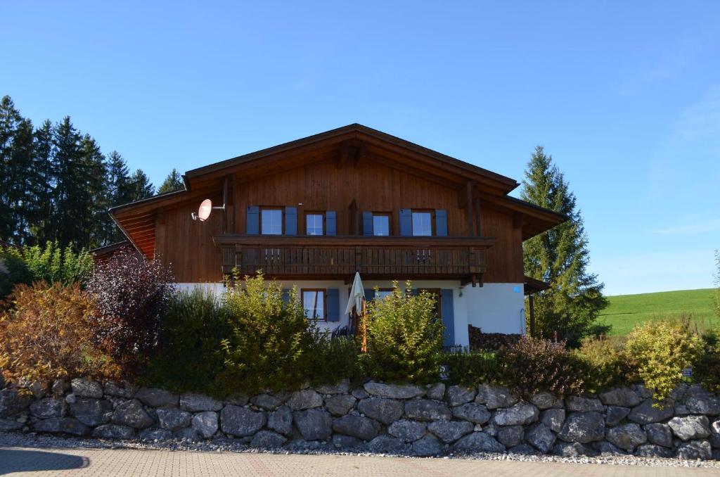 a large wooden house with a stone wall at Feriendorf Via Claudia Haus 100 Dominique in Lechbruck