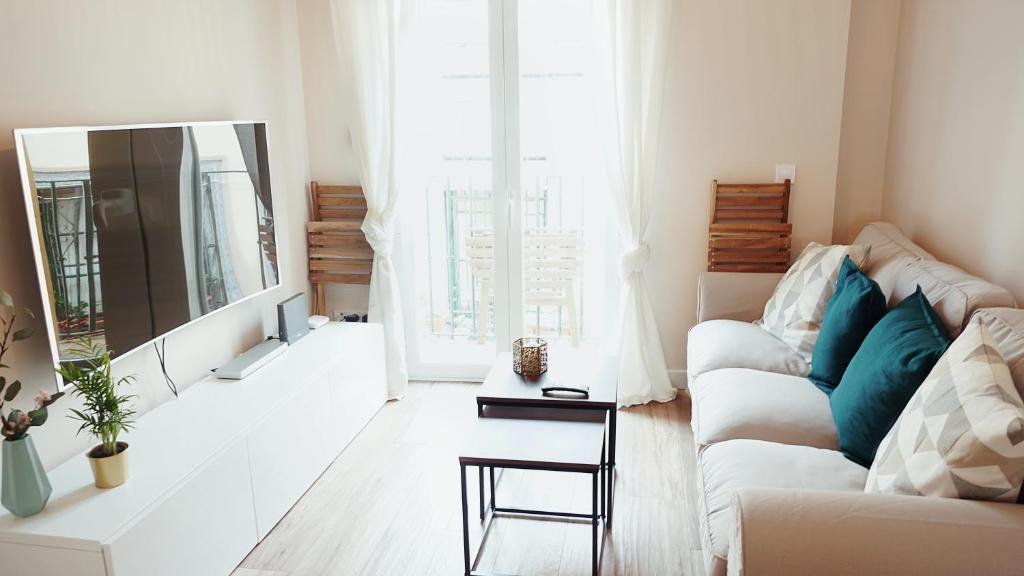 ein Wohnzimmer mit einem weißen Sofa und einem Spiegel in der Unterkunft RentalSevilla Luminoso apartamento en pleno centro in Sevilla
