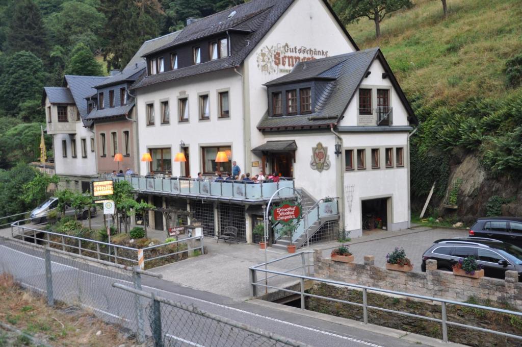 un grand bâtiment blanc sur le côté d'une route dans l'établissement Gutsschänke Sennerhof, à Oberwesel