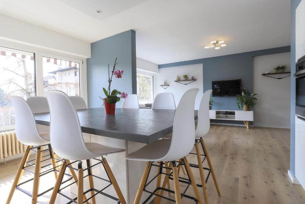 une salle à manger avec une table noire et des chaises blanches dans l'établissement Azur Bleu 4 étoiles Annecy centre-ville et lac lumineux, à Annecy