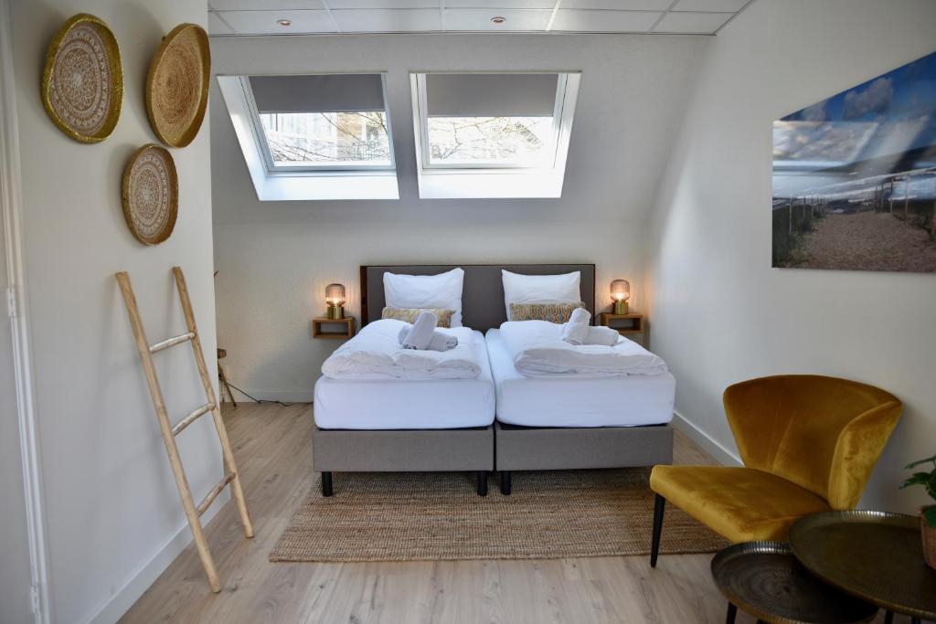 a bedroom with two beds and a table and chairs at Hofje van Maas in Zandvoort