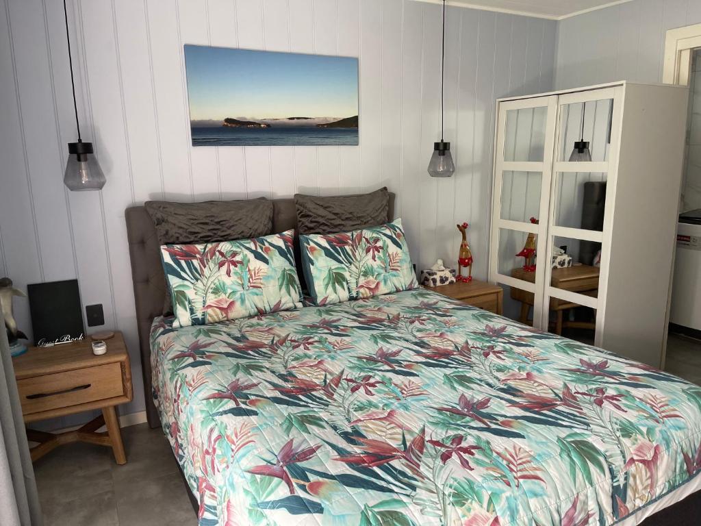 a bedroom with a bed with a floral bedspread at Agapi on Cambridge in Umina