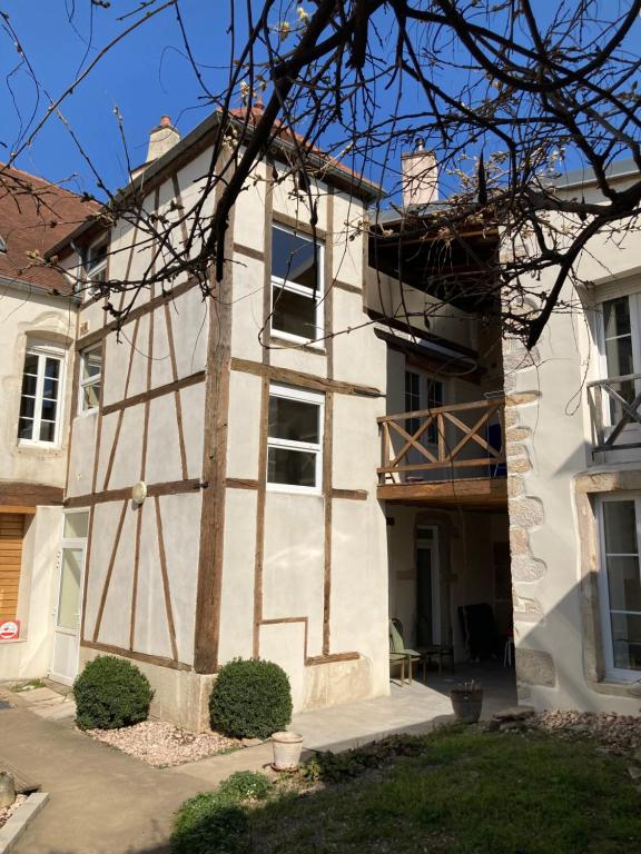 ein weißes Gebäude mit einer Veranda und einem Balkon in der Unterkunft Appart' Au Coeur de Nuits in Nuits-Saint-Georges