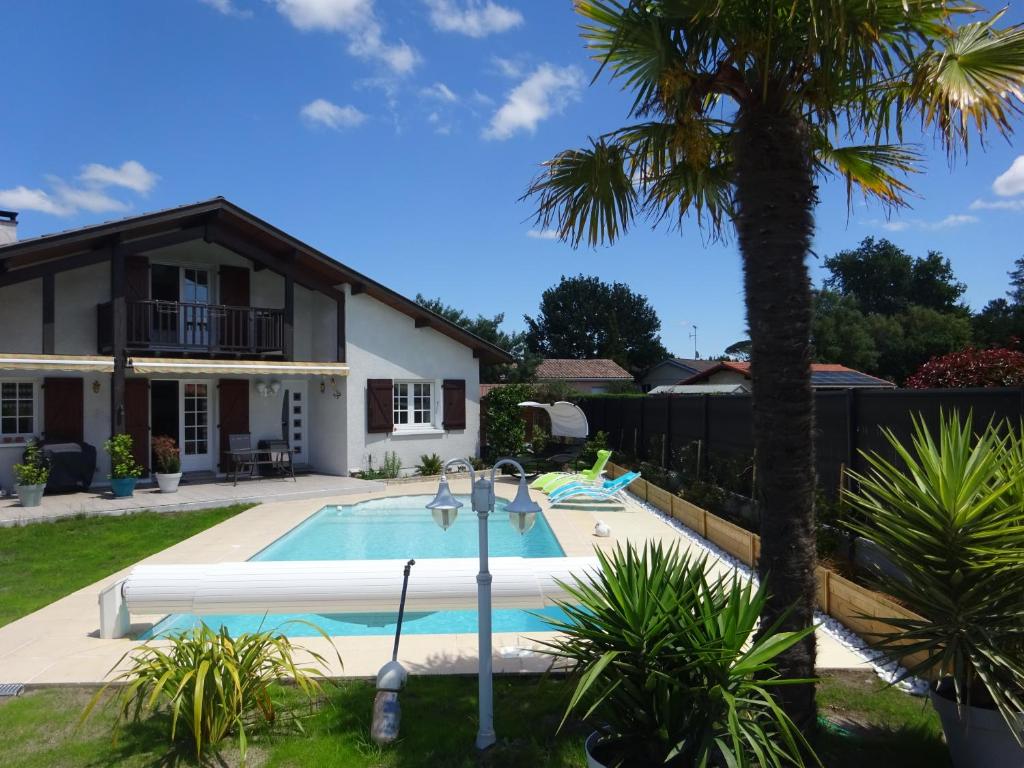 una piscina frente a una casa con palmeras en Maison familiale Landaise pour 2 couples, enfants, en Azur