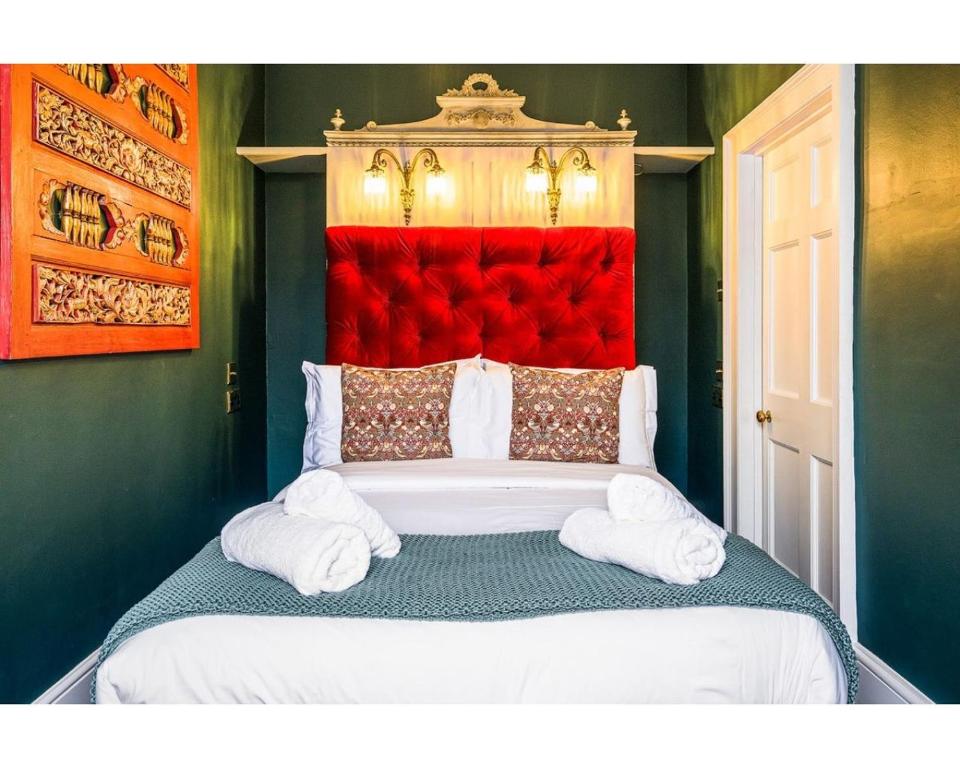 a bedroom with a large bed with a red headboard at Bennett's Lodgings a luxurious 2 bed apartment in Bath