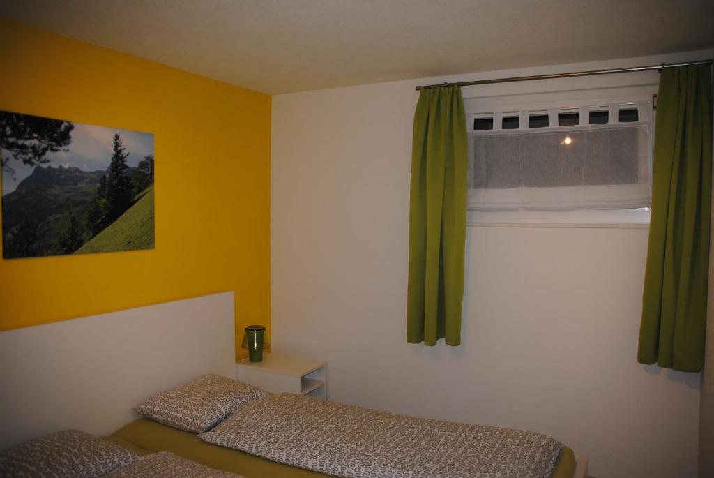 um quarto com uma cama e uma janela com cortinas verdes em Ferienwohnung Grütter em Seedorf