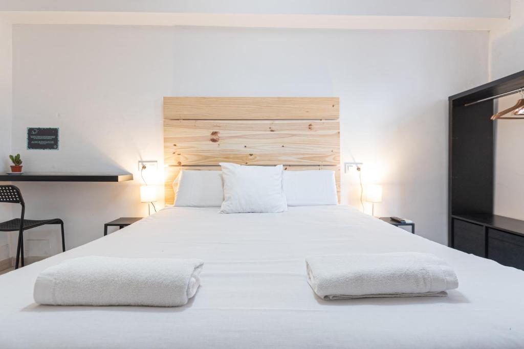 um quarto com uma grande cama branca e 2 almofadas em Easy Sants by Bossh! em Barcelona