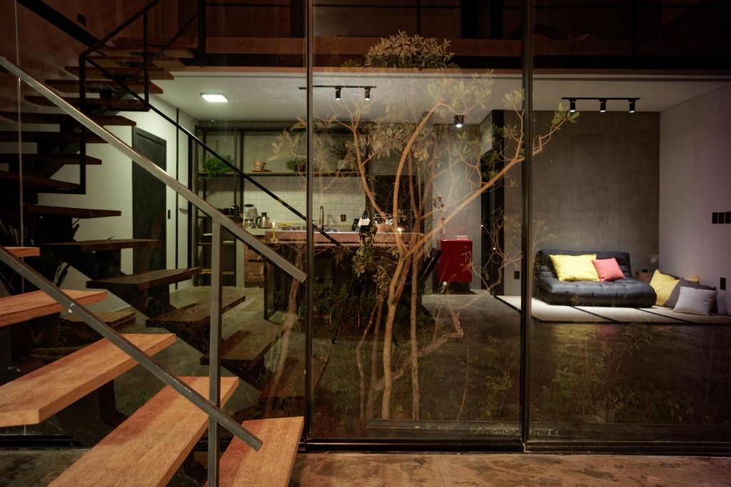 a living room with a staircase and a glass wall at Casa Nuvem Lotf House + Suíte in Alto Paraíso de Goiás