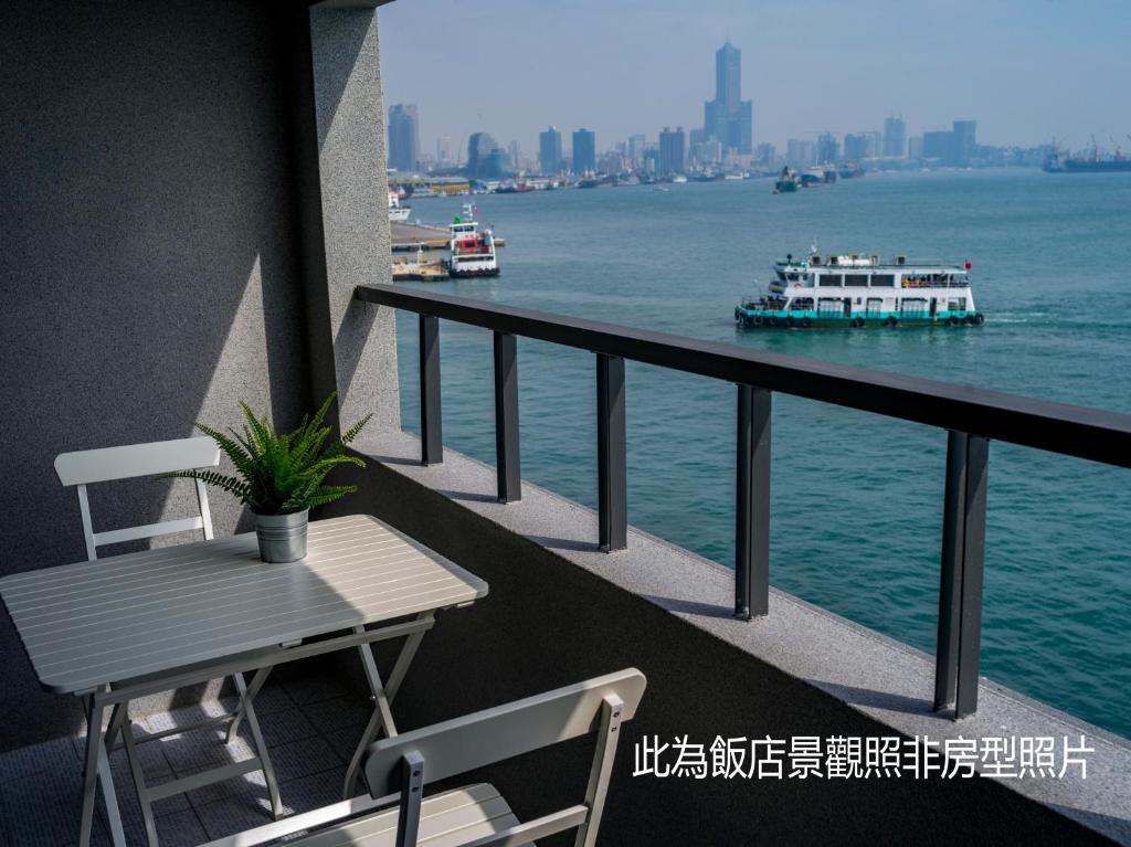 Un balcón con una mesa y dos barcos en el agua en Watermark Hotel-The Harbour en Kaohsiung