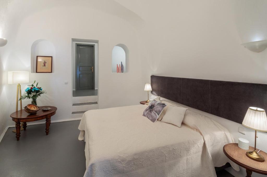 sypialnia z dużym łóżkiem i dwoma stolikami w obiekcie Azure Villa Santorini w Imerovíglion