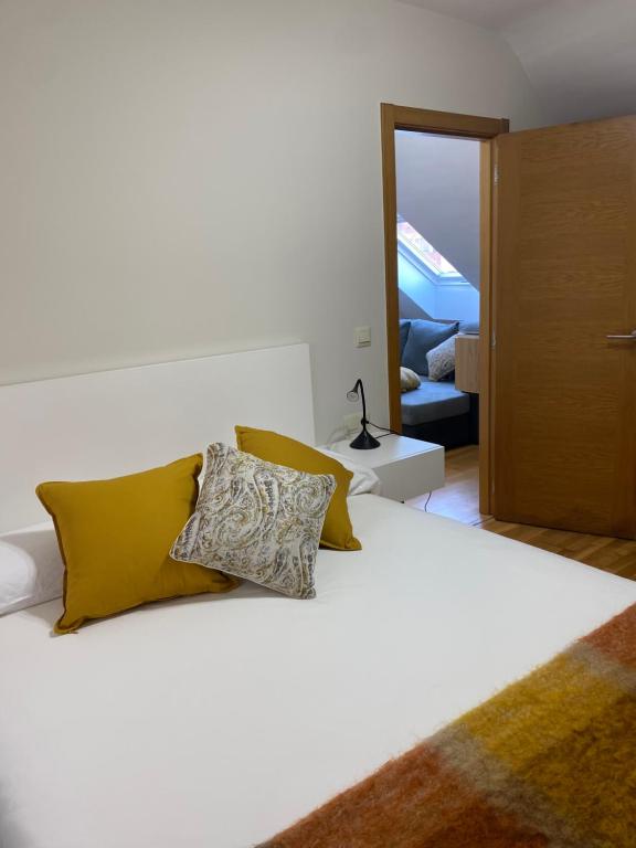 ein Schlafzimmer mit einem weißen Bett und gelben Kissen in der Unterkunft O SECRETO in Padrón