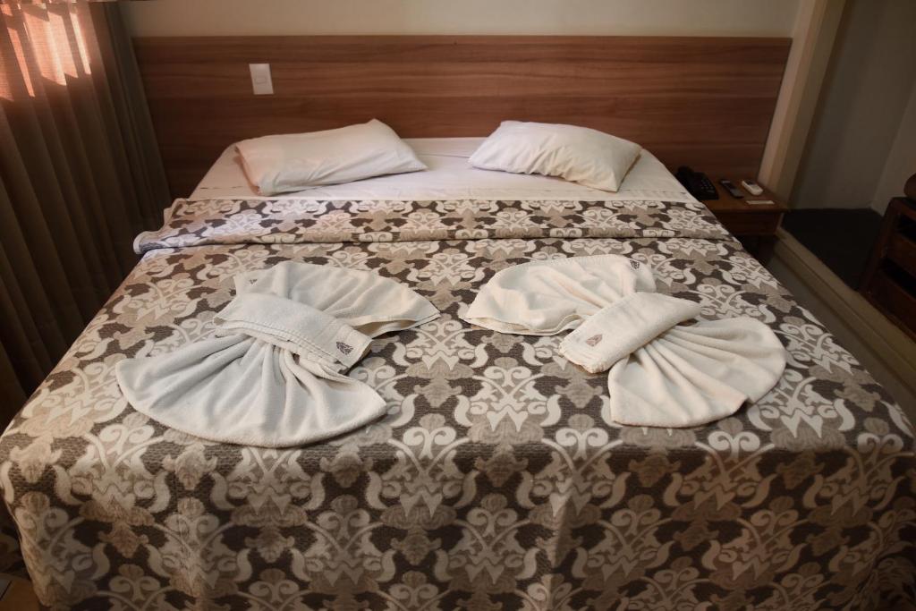 ein Bett mit zwei Hüten und Handtüchern darauf in der Unterkunft Hotel Itamarati in Sao Jose do Rio Preto