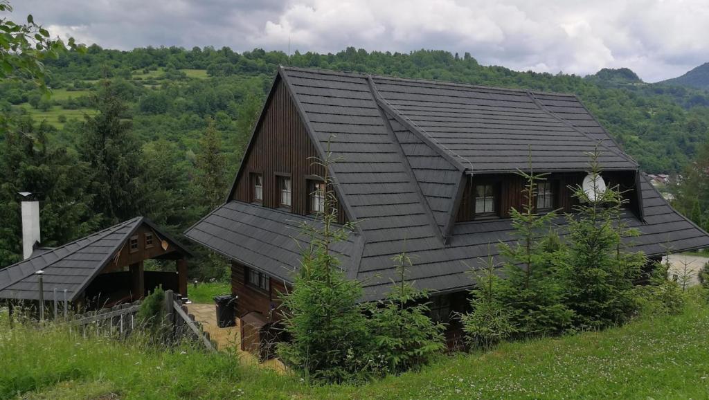 a house with a black roof on a hill at Drevenica Pod Vŕškom in Terchová