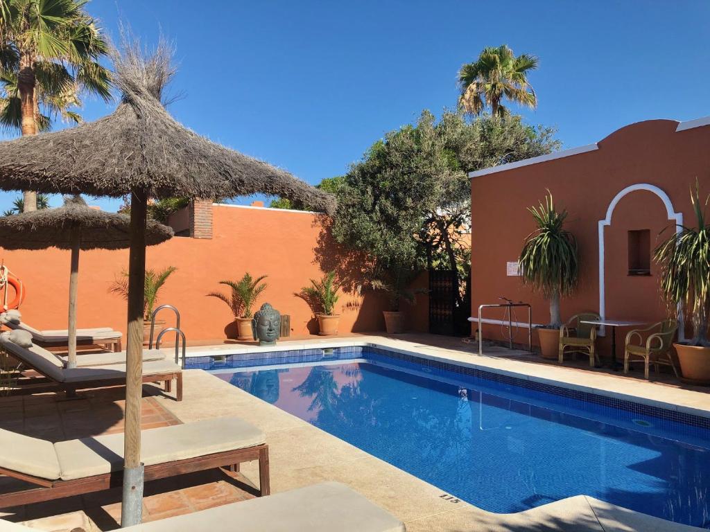 una piscina con sillas y sombrillas junto a un edificio en Hotel Madreselva en Los Caños de Meca