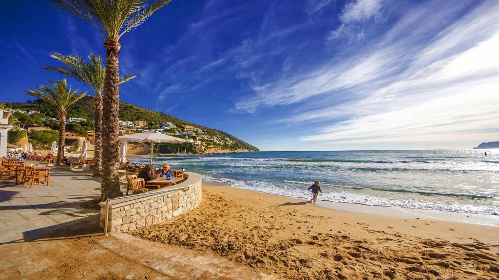 una persona caminando por la playa cerca del océano en Strandnahe Wohnung mit Meerblick en Moraira