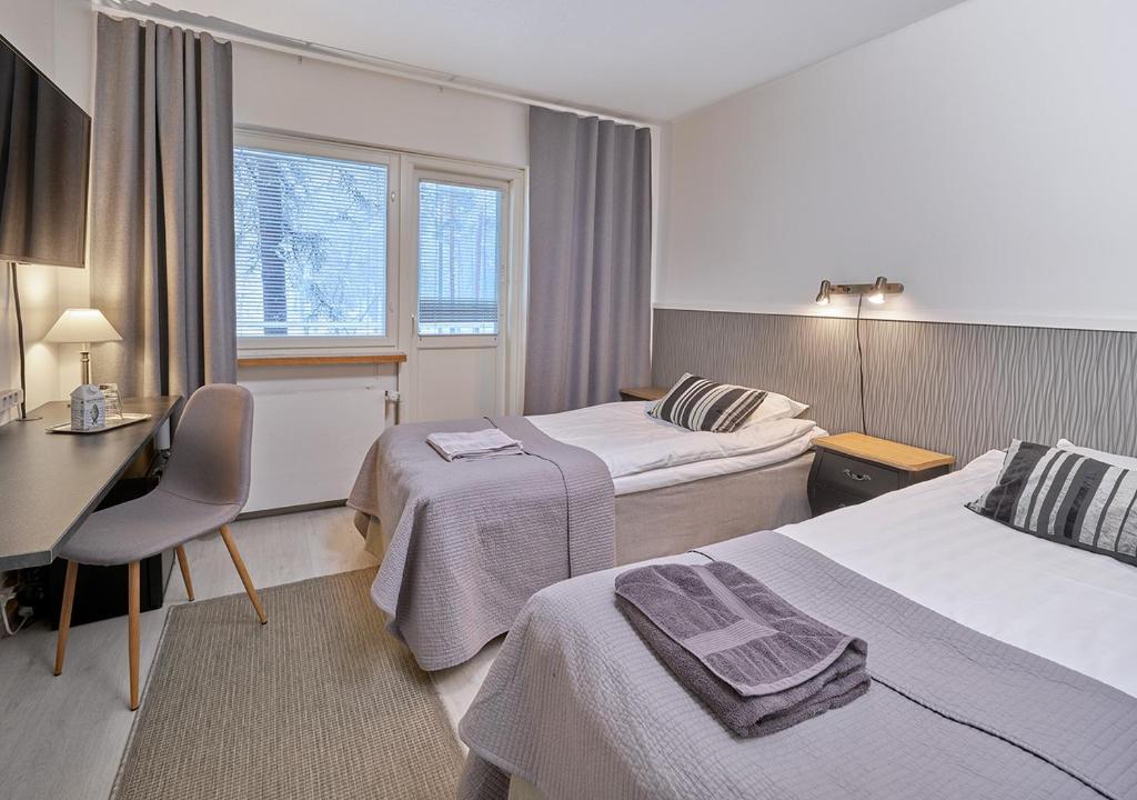 a hotel room with two beds and a desk at Hotelli-Ravintola Gasthaus Lohja in Lohja