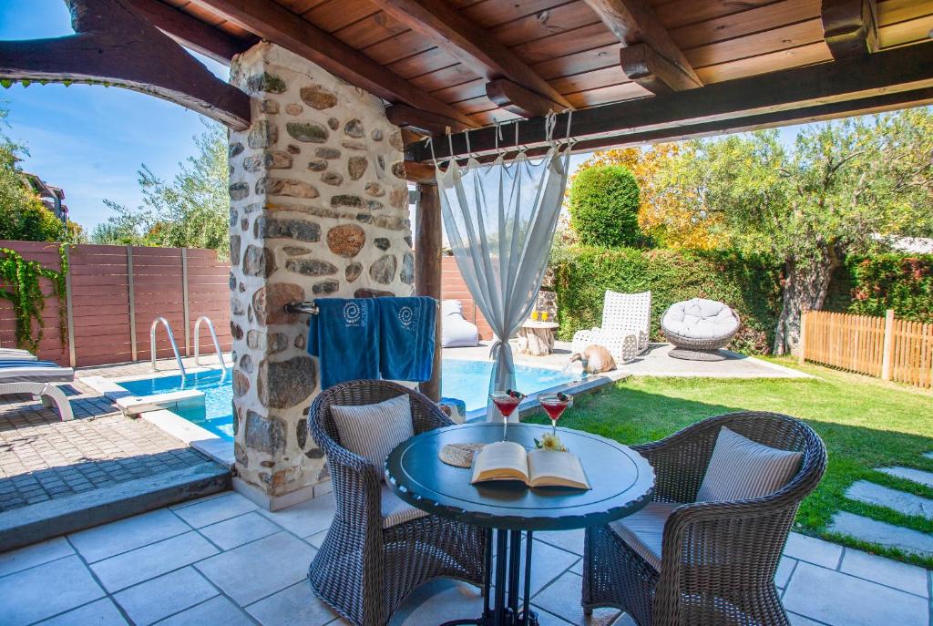 un patio con mesa, sillas y piscina en Acrotel Athena Residence en Elia