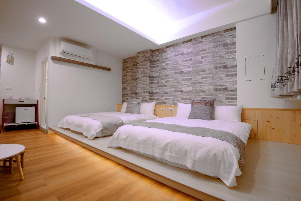 花蓮市にあるMixa Hostelのレンガの壁、ベッド2台が備わるベッドルーム1室が備わります。