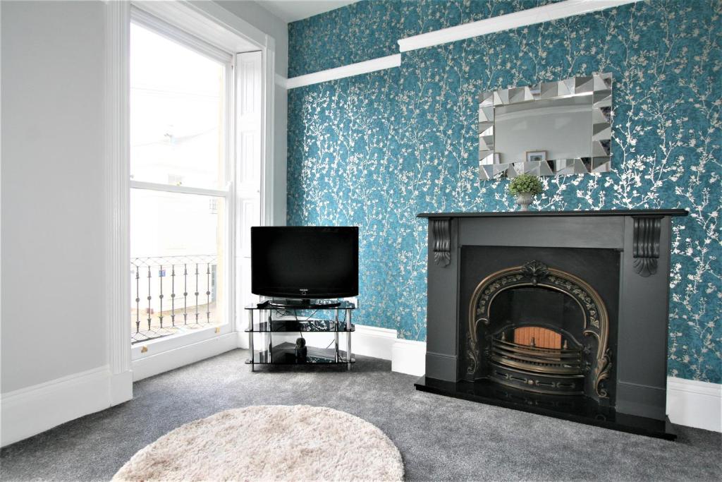 
a living room with a fire place next to a fireplace at Central Serviced Apartments by Roomsbooked in Cheltenham
