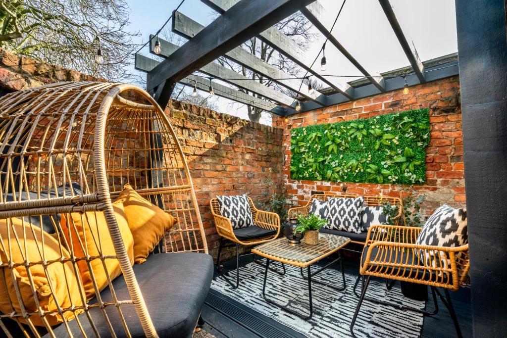 a patio with a swing and chairs and a brick wall at 46 Nunnery Lane in York