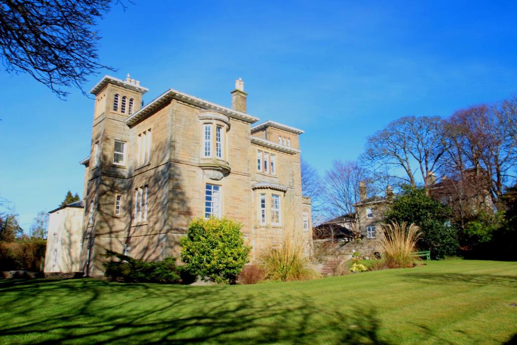 - un ancien bâtiment en pierre avec une tour sur une pelouse dans l'établissement Beautiful 2 to 3 bed apartment with stunning views!, à Ayr