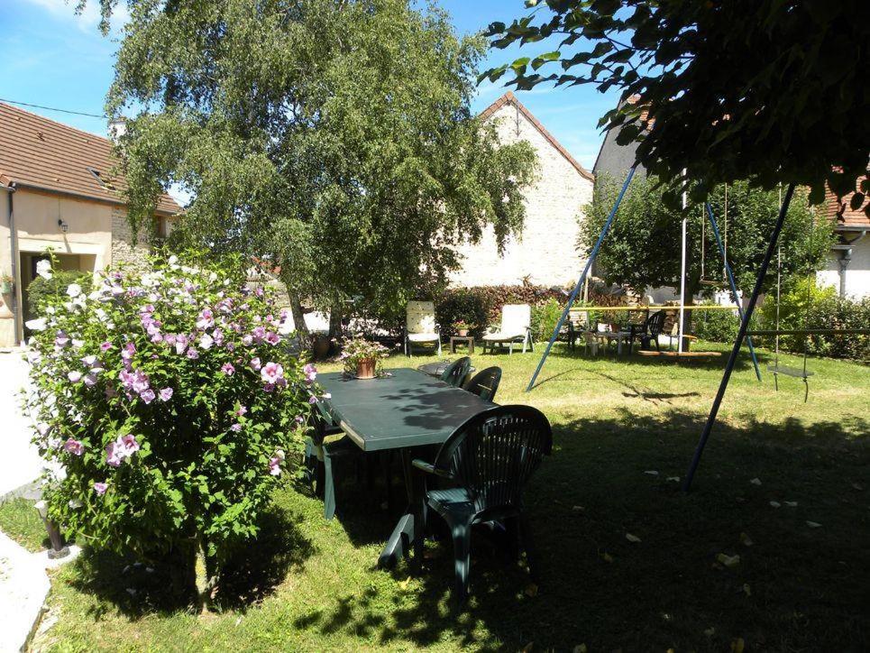 a table and chairs in a yard with a bush at Le Caméléon in Corgoloin