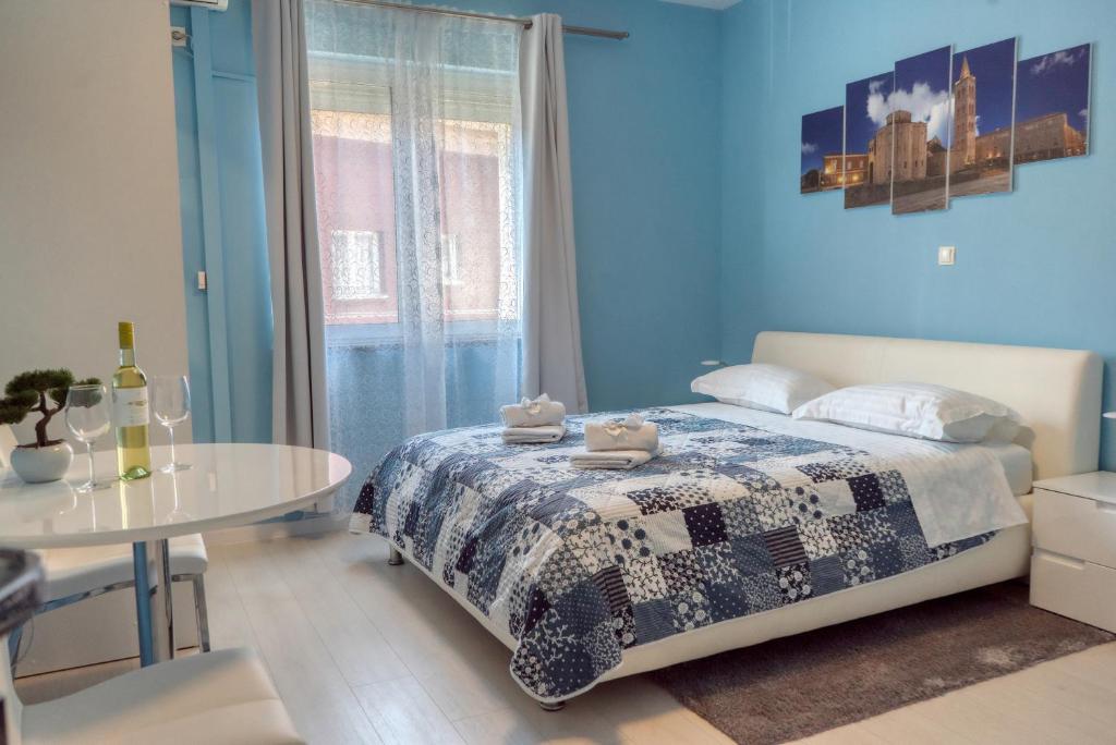 - une chambre bleue avec un lit et une table dans l'établissement Apartments & Rooms Andrea 2, à Zadar