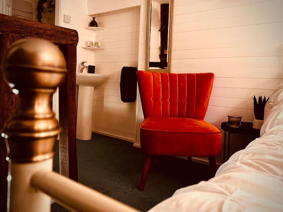 a bedroom with a red chair and a sink at Outhouse Bothy in Kirkby Lonsdale