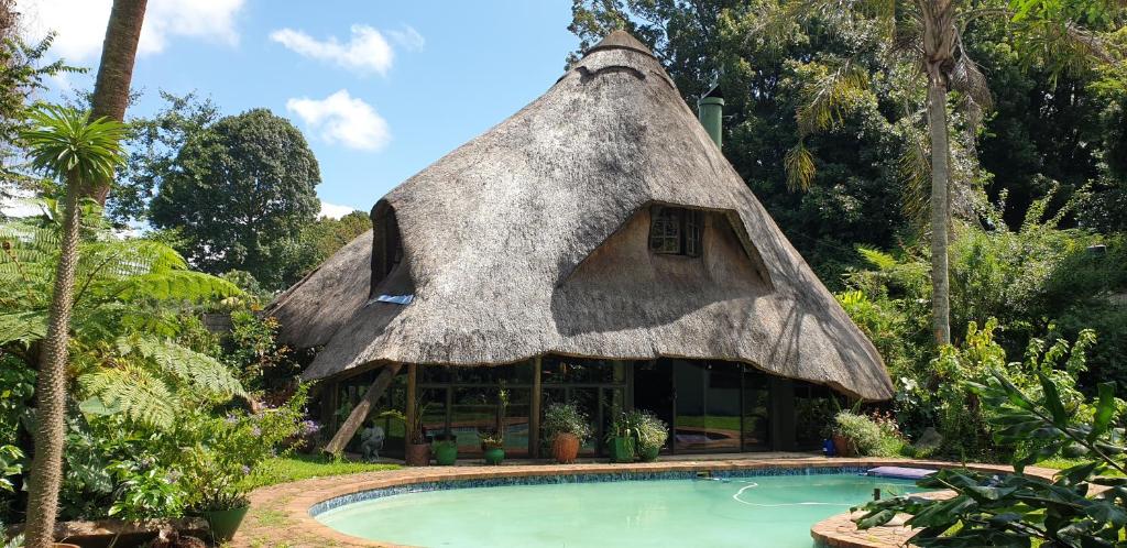 a thatched house with a swimming pool in front of it at The Lapa in Durban