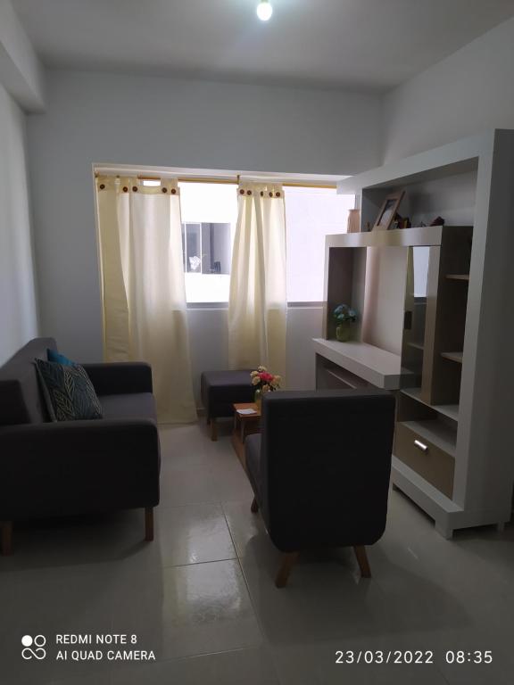 een woonkamer met een bank en stoelen en een raam bij Apartamento Loft in Bucaramanga