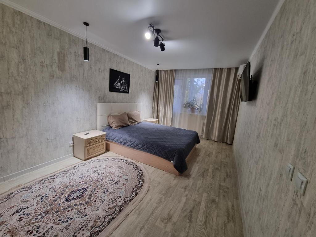 - une chambre avec un lit, un tapis et une fenêtre dans l'établissement Посуточная квартира на Кердери с Wi-Fi, à Uralsk