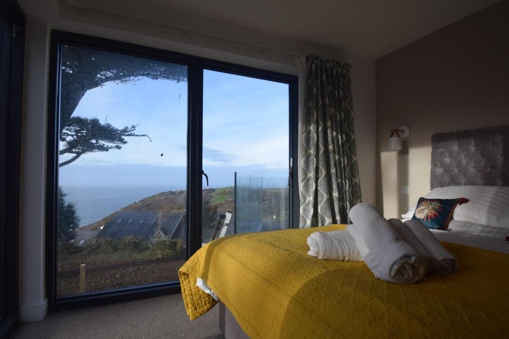 Un dormitorio con un gran ventanal con vista al mar. en Flat 2 High Tide House - Stylish flat with large terrace and incredible sea views, en Mortehoe
