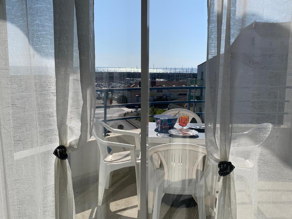 a white table and chairs on a balcony with a window at Appartement vue sur mer in Talmont