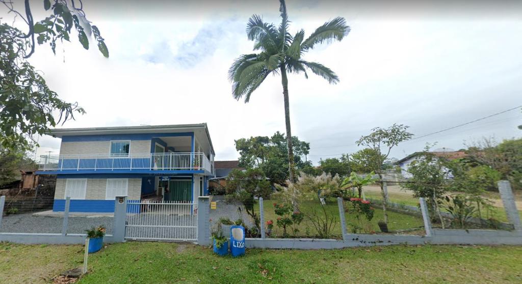 a house with a palm tree behind a fence at Paraíso dos Accácio in Balneario Barra do Sul