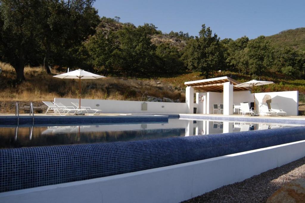 a swimming pool with a table and an umbrella at Quinta da Saimeira in Marvão