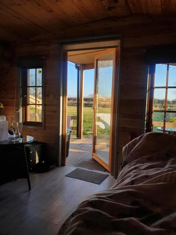 Schlafzimmer mit einem Bett und einer Glasschiebetür in der Unterkunft Beautiful Wooden tiny house, Glamping cabin with hot tub 2 in Tuxford