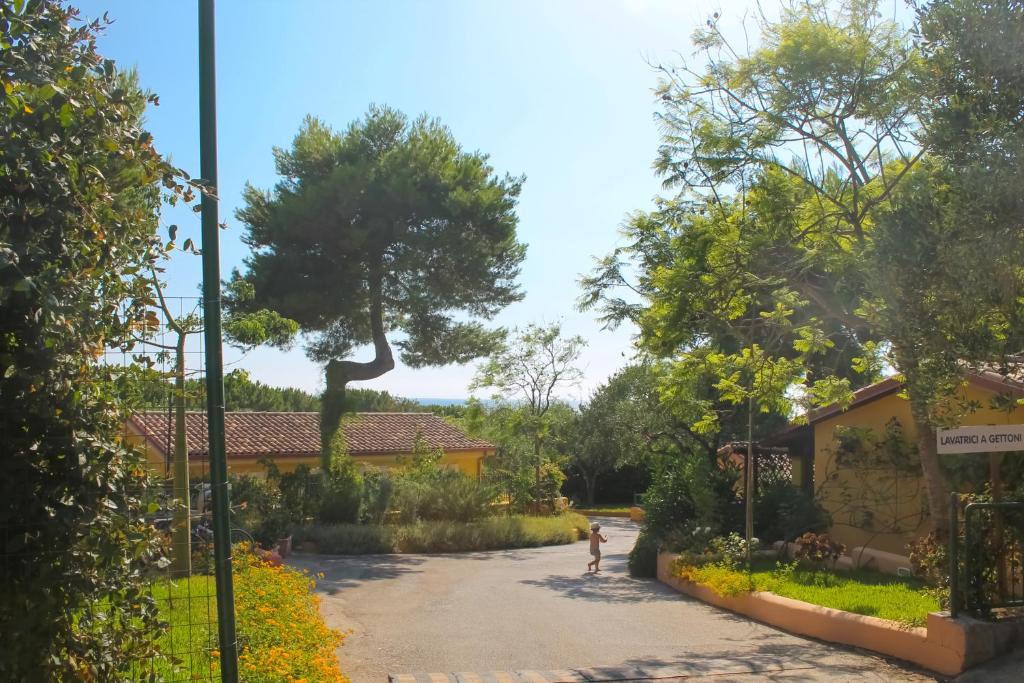 a child walking down a driveway in a garden at Villaggio La Perla in Marina di Camerota