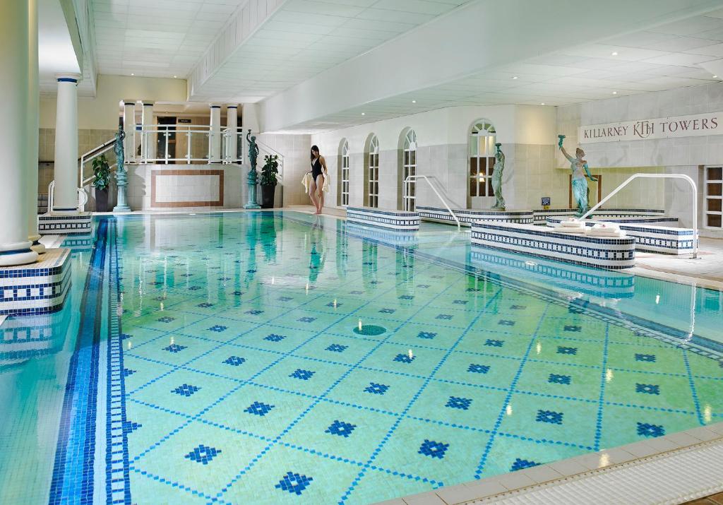 a swimming pool with a woman standing in the middle of it at Killarney Towers Hotel & Leisure Centre in Killarney