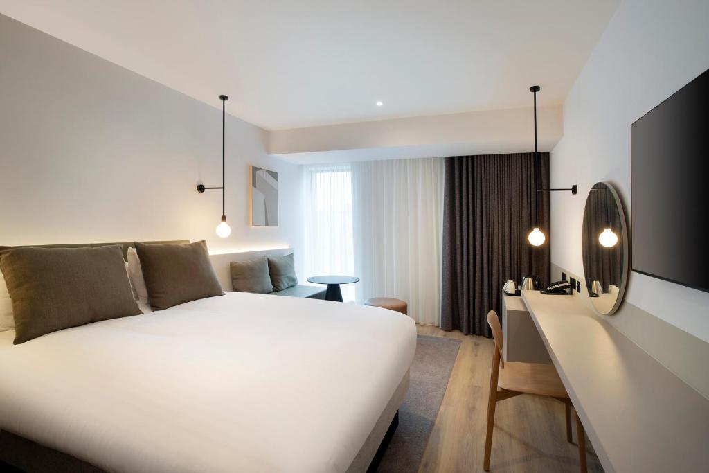 1 dormitorio con 1 cama blanca grande y escritorio en Leonardo Hotel Manchester Piccadilly en Mánchester